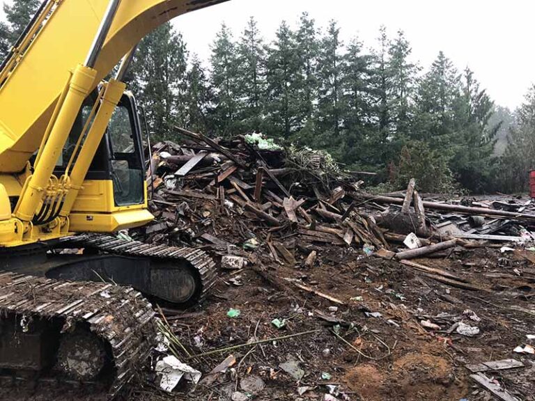 An excavator working a demolition debris pile on a cleared job site